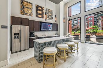 A kitchen with a refrigerator, stove, and bar stools.